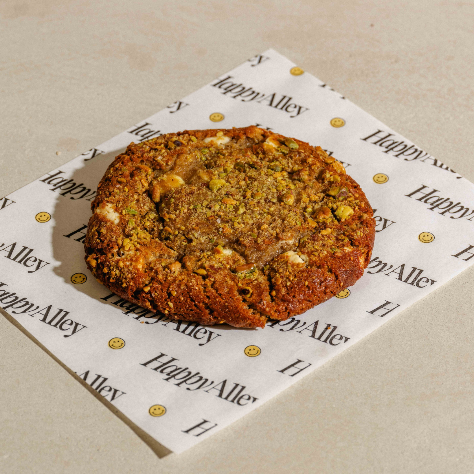 Date Pistachio Cookie on a piece of paper with 'Happy Alley' branding on a beige surface